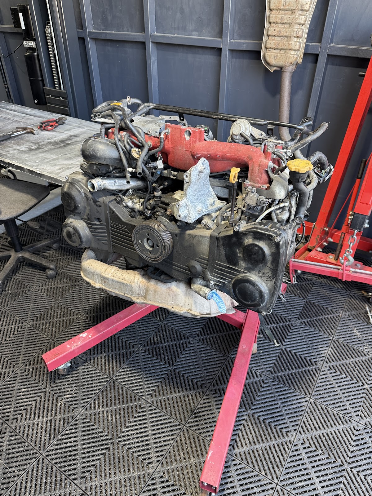 Subaru engine with red intake manifold on an engine stand